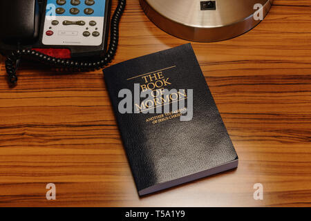 Easton, MD - 5 Avril 2019 : Le Livre de Mormon est assis dans une chambre d'hôtel lit table à côté de la lampe et téléphone. Banque D'Images