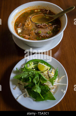 Un bol de Pho boeuf épicé aux légumes et herbes sur le côté. L'alimentation de rue vietnamienne qui est devenu populaire aux Etats-Unis et dans d'autres pays. Banque D'Images