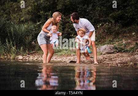 Une jeune famille avec deux enfants enfant passer du temps à l'extérieur de la rivière en été, d'avoir du plaisir. Banque D'Images