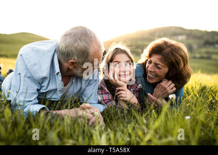 Close-up of a senior couple avec sa petite-fille à l'extérieur au printemps nature, couché dans l'herbe et se détendre. Banque D'Images