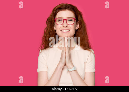 Reconnaissant redhead girl avec la prière mains sentir reconnaissant Banque D'Images