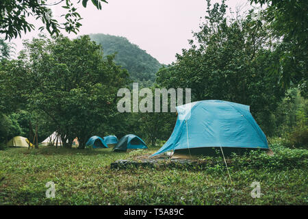 Camp touristique avec beaucoup de tentes dans les bois. Tente dôme couleur bleu ciel et paysages de montagnes en arrière-plan Banque D'Images