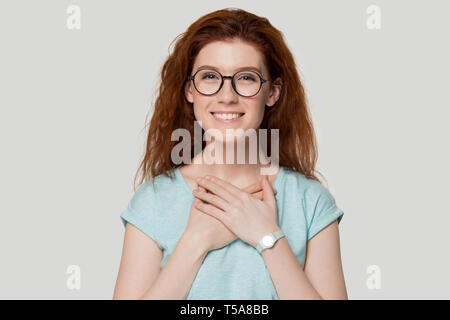 Smiling reconnaissant fille rousse dans les verres avec les mains sur la poitrine Banque D'Images