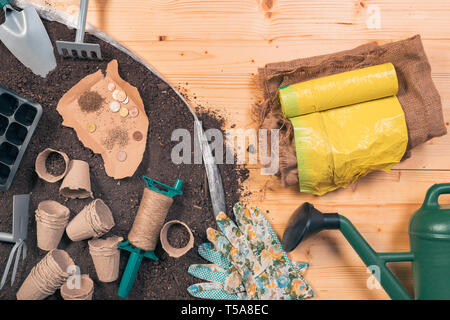 La production d'aliments biologiques peu coûteux et équipements de jardinage, vue du dessus d'outils et de semences sur table en bois dans jardin avec quelques pièces en euro concept de l Banque D'Images