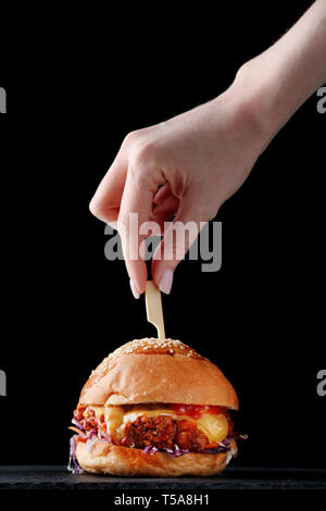 Burger avec brochette sur bois. Les mains tiennent brochette Banque D'Images