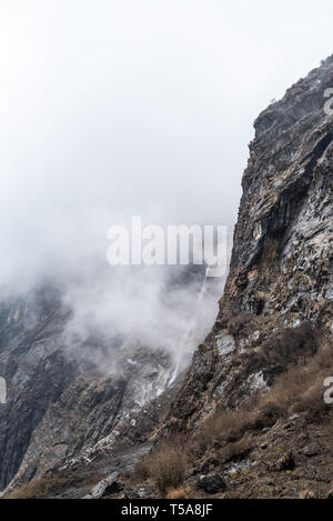 Falaise de montagne brumeuse avec chute d'eau sur la route de trekking dans le circuit Annapurna. Népal Banque D'Images