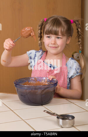 Petite fille de cinq ans en remuant la pâte d'un gâteau bundt chocolat. (MR) Banque D'Images