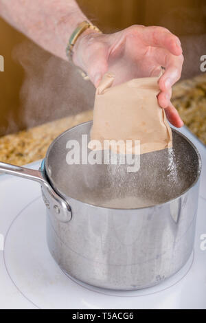 Woman pouring pectine de fruits dans la casserole pour faire de la confiture. Pectine de fruits est produit commercialement comme une poudre blanche à brun clair, principalement extraits de citrus Banque D'Images