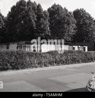 Années 1950, historcial, après-guerre de maisons préfabriquées, connu sous le nom de 'préfabriqués', Angleterre, Royaume-Uni. Pour répondre à la pénurie de logements APRÈS LA SECONDE GUERRE MONDIALE, quelque 150 000 maisons ont été construites. Avec un projet de vie de seulement 10 ans, beaucoup ont survécu pendant des décennies, plus de prouver leur bonne conception et de la construction. La recherche rigoureuse a vu les innovations, ainsi que pour les feux de charbon, ils contenaient des chaudières pour chauffage central et eau chaude, ainsi que d'un four et d'un réfrigérateur dans la cuisine. Comme on le voit ici, beaucoup ont été deveoped sur le côté de parcs depuis, donnant le sentiment d'habitants vivent dans les campagnes. Banque D'Images