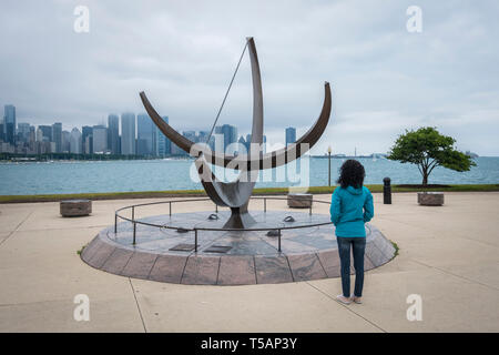 Femme regarde l'homme entre dans le Cosmos sculpture à côté du Planétarium Adler avec horizon de Chicago dans l'arrière-plan Banque D'Images