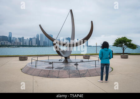 Femme regarde l'homme entre dans le Cosmos sculpture à côté du Planétarium Adler avec horizon de Chicago dans l'arrière-plan Banque D'Images