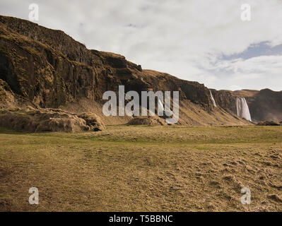 Pré sur un versant de montagne avec plusieurs chutes d'eau en Islande Banque D'Images