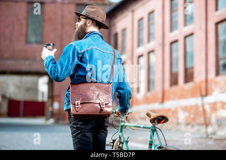 Hipster style rétro avec café et marche vélo sur l'arrière-plan urbain industriel, vue arrière Banque D'Images