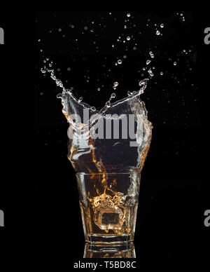 Shot de whiskey isolé avec splash sur fond noir Banque D'Images
