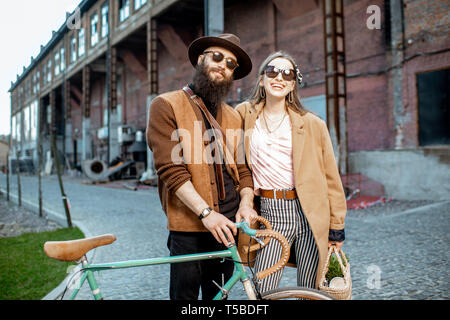 Portrait of a man and woman standing élégant ensemble avec retro location en plein air sur le fond urbain industriel Banque D'Images