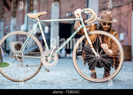 Hipster barbu habillé élégamment avec hat standing avec retro location en plein air sur l'arrière-plan urbain Banque D'Images