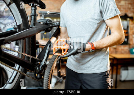 Réparateur installer de nouvelles pédales sur un vélo de montagne à l'atelier Banque D'Images