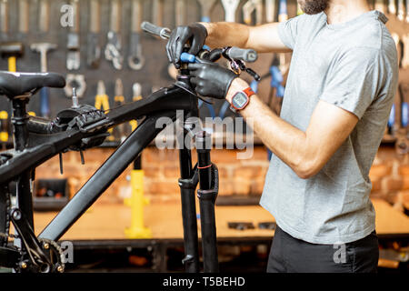 L'homme de retirer le volant à partir de la bicyclette à l'atelier Banque D'Images