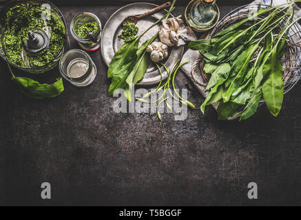 Ramson, l'ail sauvage, du pesto avec des ingrédients sur la table de cuisine rustique sombre arrière-plan, Vue de dessus, de frontière. Copie de l'espace pour votre conception, texte ou recettes. Sp Banque D'Images