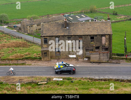 Marsden, Yorkshire, 23 avril 19. Une voiture de police arrête un civil de conduire au-delà de la route fermée signe, en tant que cycliste rides passé vers les feux sauvages. Banque D'Images