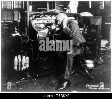 Thomas Edison (1847-1931) à son bureau, parler au téléphone, montrant un cylindre de cire mémoire vocale et les cylindres, 1914 Banque D'Images