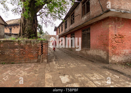 BHAKTAPUR, NÉPAL - 5 avril, 2019 : Femme portant des vêtements rouge à proximité à pied d'un immeuble industriel, pris dans un ciel couvert matin dans la histori Banque D'Images