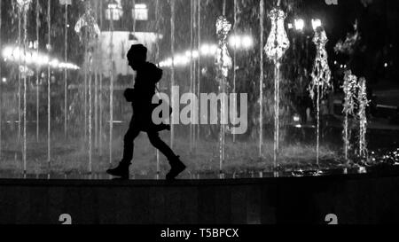 Fille qui marche la fontaine frontière. En tant que noir et blanc stylisé silhouette Banque D'Images