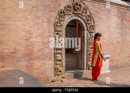 Kathmandu, Patan, NÉPAL - 3 avril, 2019 : Jeune femme frappant une pause de l'appareil photo en face d'une de la porte du Palais Royal Banque D'Images