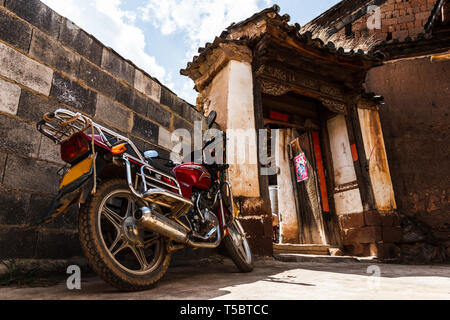 Old school moto garée devant une maison dans un village Banque D'Images