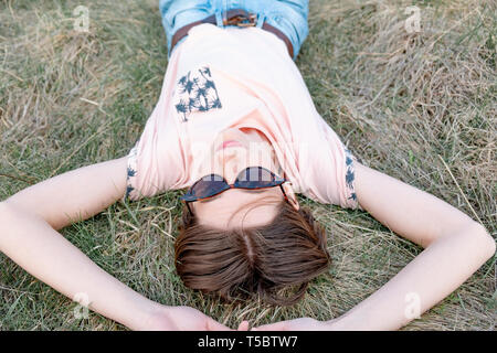 Jeune femme repose sur l'herbe profitant du printemps. Vue de dessus d'une personne de sexe féminin dans le pré de pose ou un champ de regarder le ciel Banque D'Images