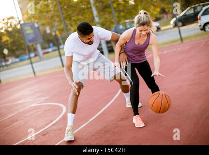 Groupe de jeunes Les jeunes multiethniques jouant au basket-ball sur cour Banque D'Images