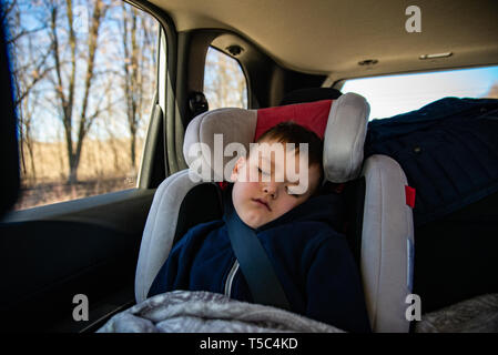 Petit enfant dormant dans location de fauteuil à l'arrière en road trip. Banque D'Images