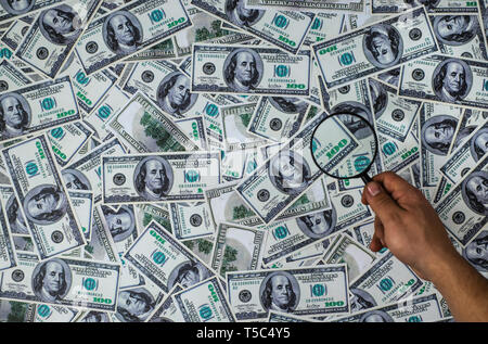 Man holding Magnifying Glass sur les cent dollars américains background Banque D'Images