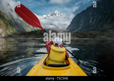 Jeune garçon en jaune vif kayak sur lac de montagne. White Mountain Peak dans l'arrière-plan Banque D'Images