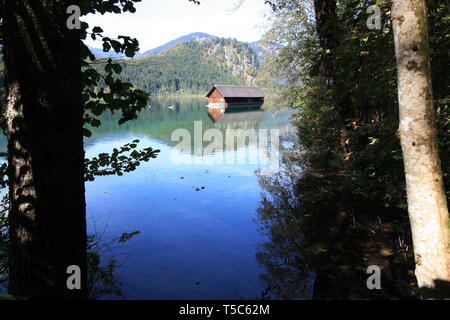 Un hangar à bateaux en bois traditionnels reflétant sur l'eau cristalline de la Almsee, près de Grünau im Almtal, Oberösterreich, Autriche Banque D'Images