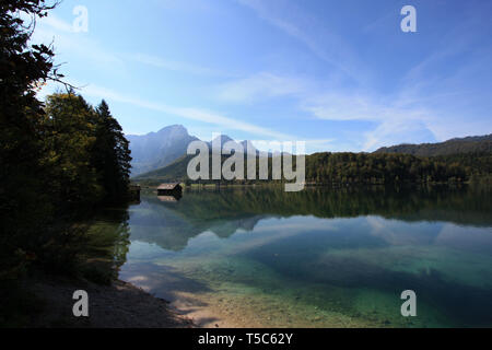 Un hangar à bateaux en bois traditionnels reflétant sur l'eau cristalline de la Almsee, près de Grünau im Almtal, Oberösterreich, Autriche Banque D'Images