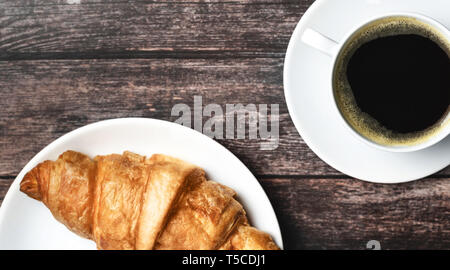 Le petit déjeuner parfait de croissant et café sur table en bois. Style rustique. Banque D'Images