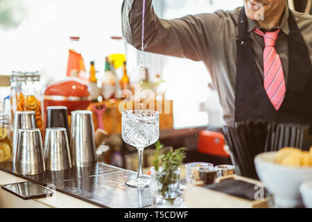 Le mélange d'un barman cocktail dans un verre de cristal dans un bar américain - Barman verser de l'alcool dans un verre avec des herbes aromatiques Banque D'Images