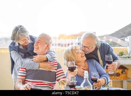 Happy friends having fun boire du vin rouge en terrasse en plein air - les personnes âgées de dîner et rire ensemble Banque D'Images