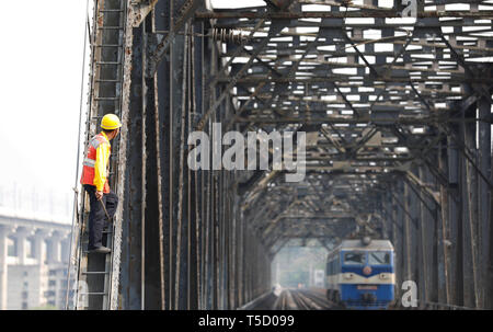 (190424) -- BEIJING, 24 avril 2019 (Xinhua) -- un travailleur attend une locomotive électrique de passer sur l'ancien pont ferroviaire de la rivière Yangtze Baishatuo dans Jiangjin de sud-ouest de la Chine, la municipalité de Chongqing, le 23 avril 2019. L'ancien pont ferroviaire de la rivière Yangtze Baishatuo, achevé en 1959, le service s'arrête après le 24 avril. Tous les trains circuleront sur la nouvelle Double Decker à treillis en acier du pont ferroviaire du séjour après ce jour. Le nouveau pont a 4 pistes sur le pont supérieur pour les trains avec une vitesse de conception de 200 kilomètres par heure et 2 pistes sur le pont inférieur pour les trains de fret wit Banque D'Images