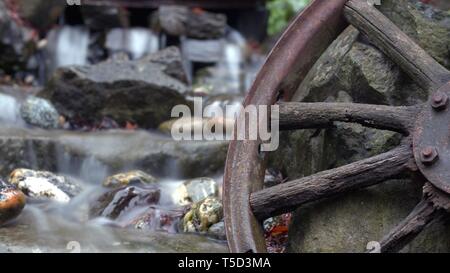Automne eau rustique descendant en un lit de rivière en pierre ancienne en bois sur roues a parlé Banque D'Images
