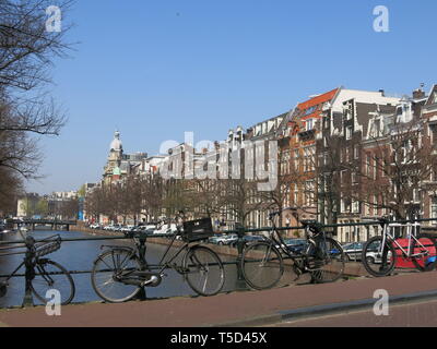 Une scène avec une rangée de vélos garés sur le parapet d'un pont sur un canal dans le centre d'Amsterdam Banque D'Images