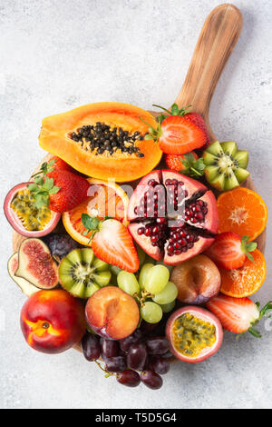 Plateau de fruits délicieux fruits de la passion oranges papaye grenade sur planche de bois sur blanc, vue du dessus, selective focus Banque D'Images