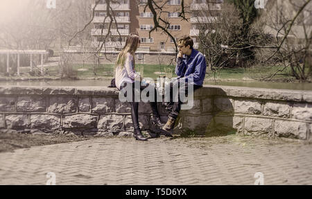 Jeune couple assis sur une digue et se détendre pendant une journée ensoleillée au printemps. Banque D'Images