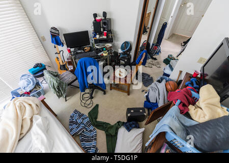 Très salissante, encombré,teenage boy's chambre avec des piles de vêtements, appareils électroniques, de la musique et des équipements sportifs. Banque D'Images