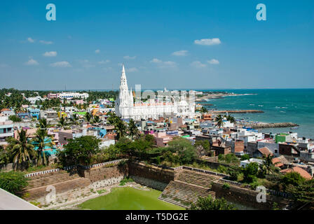 Kanyakumari, Inde - Janvier 26,2019:Notre Dame de rançon de culte Église derrière maisons colorées sur une plage de sable occupée par les bateaux de pêche à Kanyakumari Banque D'Images