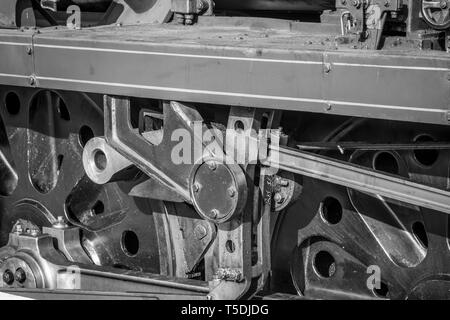 Close up noir et blanc vintage UK de roues de la locomotive à vapeur. Vue latérale du train à vapeur avec roues d'entraînement bielle de liaison. Banque D'Images