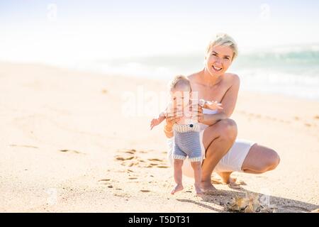 Belle mère blonde avec 4 mois bébé garçon sur la plage, Portugal Banque D'Images