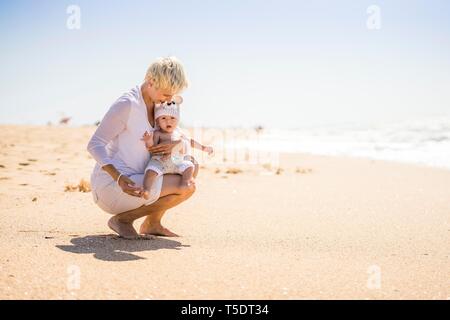 Belle mère blonde avec 4 mois bébé garçon sur la plage, Portugal Banque D'Images