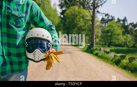 Méconnaissable Jeune homme posant avec un casque de moto et des gants au milieu de la route Banque D'Images